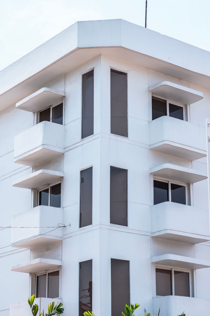 Modern white building with angular design and balconies against a clear sky.