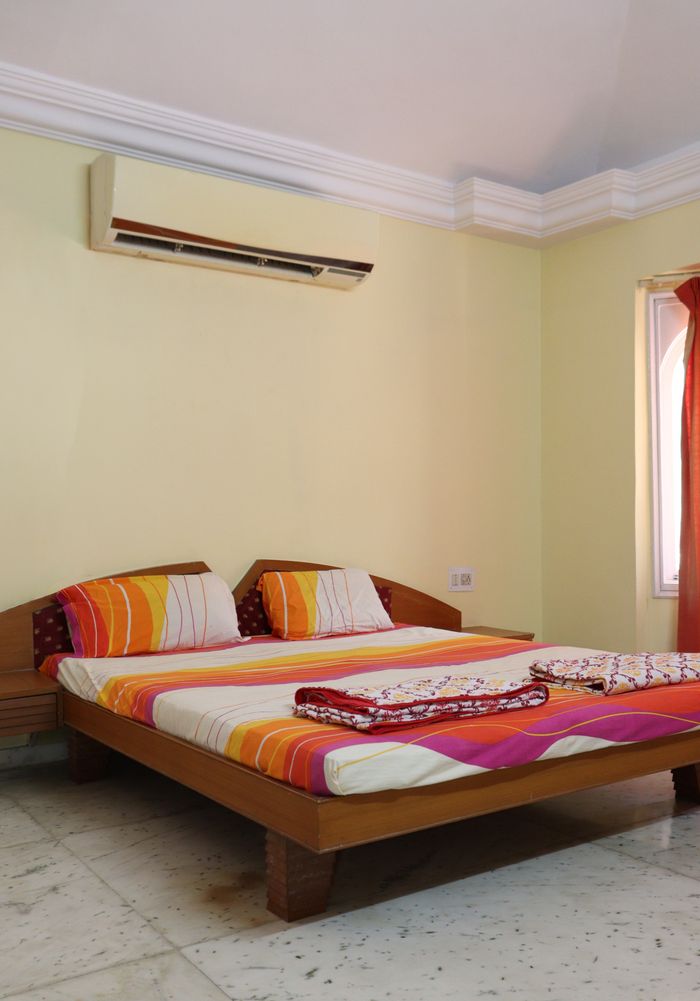 Services A cozy bedroom in Ahmedabad featuring a double bed with vibrant bedding.