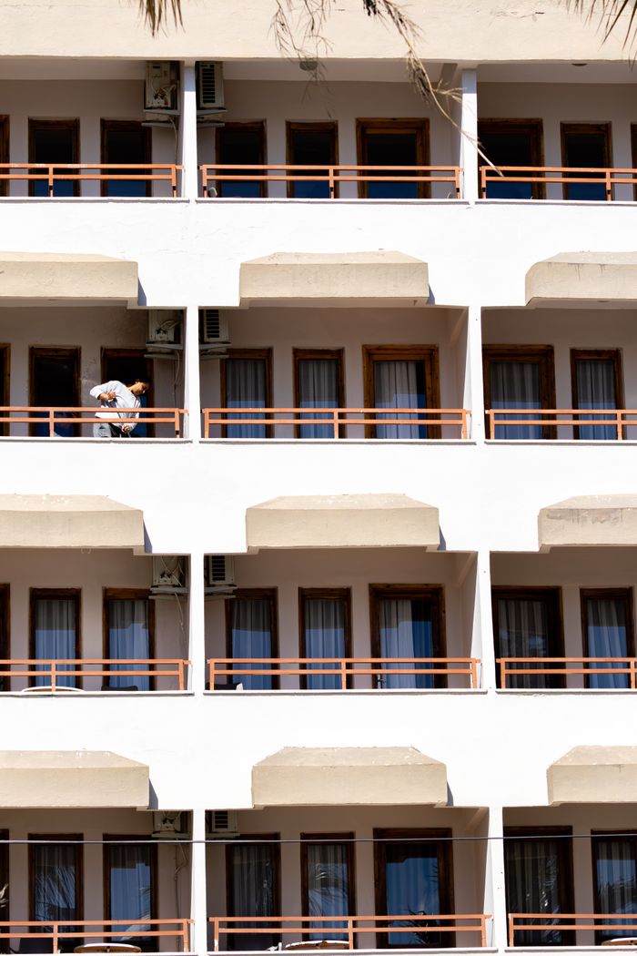 About Symmetrical hotel facade showcasing balconies with a person outdoors, captured in daylight.